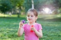 A little girl blowing soap bubbles in a park Royalty Free Stock Photo