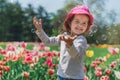 Little girl blowing soap bubbles in summer park and blooming tulips Royalty Free Stock Photo