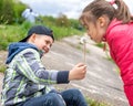 Little girl blows on a dandelion that the boy is holding Royalty Free Stock Photo