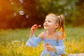 A little girl blows soap bubbles
