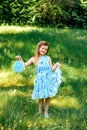 Little girl in a blue dress with a blue bag in summer garden Royalty Free Stock Photo