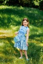 Little girl in a blue dress with a blue bag in summer garden Royalty Free Stock Photo