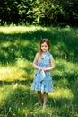 Little girl in a blue dress with a blue bag in summer garden Royalty Free Stock Photo