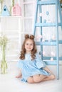 Little girl in blue dress decorates house for holiday of Easter. Blue decorative staircase with garland of color Easter eggs. East