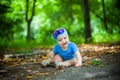 Little girl in blue dress and headband with flowers sitting on ground in Park. Royalty Free Stock Photo