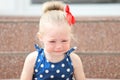 Little girl in a blue dress sits on the steps and cries Royalty Free Stock Photo