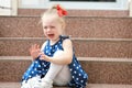 Little girl in a blue dress sits on the steps and cries Royalty Free Stock Photo