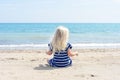 Little girl in blue dress sitting on the beach enjoying a beautiful day Royalty Free Stock Photo
