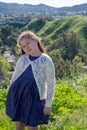 Little Girl in Blue Dress Smiling in Front of Field with Flowers and Hills in background Royalty Free Stock Photo