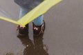 A little girl in a blue jacket under an umbrella walks on a wet sidewalk on a rainy day in spring or autumn Royalty Free Stock Photo