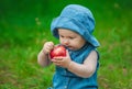 Little girl in blue jeans and a hat on his head in a blue dress sitting on a sunny day in the park on the grass Royalty Free Stock Photo