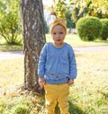 a little girl in a blue shirt and yellow pants stands on the lawn in the park. Royalty Free Stock Photo