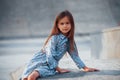 Little girl in blue wear posing for a camera in the city when leaning on the ramp Royalty Free Stock Photo