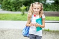 Little girl with book and backpack in school park. The concept of school, study, education, friendship, childhood Royalty Free Stock Photo