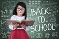 Little girl with book and doodles on chalkboard Royalty Free Stock Photo