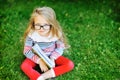 Little girl with a book in a park wearing glasses portrait Royalty Free Stock Photo