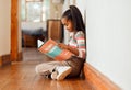 Little girl, book and reading on wooden floor for learning, education or story time relaxing at home with smile. Happy Royalty Free Stock Photo