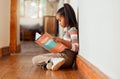 Little girl, book and reading on wooden floor for story time, learning or education relaxing at home with smile. Happy Royalty Free Stock Photo