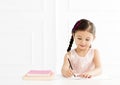 Little girl with book writing to notebook Royalty Free Stock Photo