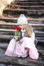 Little girl with a bouquet of red roses. Portrait of a sad child with blond hair. Spring Royalty Free Stock Photo