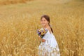 Little girl with a bouquet of wildflowers in her hands in a wheat field.