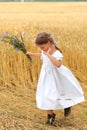 Little girl with a bouquet of wildflowers in her hands in a wheat field.