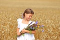 Little girl with a bouquet of wildflowers in her hands in a wheat field.