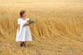 Little girl with a bouquet of wildflowers in her hands in a wheat field.