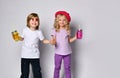 Little girl and boy in colorful casual clothes. Smiling, holding hands, yellow and pink cocktail bottles. Posing isolated on white Royalty Free Stock Photo