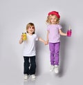 Little girl and boy in colorful casual clothes. Smiling, holding hands, yellow and pink cocktail bottles. Posing isolated on white Royalty Free Stock Photo