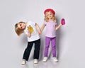 Little girl and boy in colorful casual clothes. Smiling, holding hands, yellow and pink cocktail bottles. Posing isolated on white Royalty Free Stock Photo