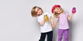 Little girl and boy in colorful casual clothes. Smiling, holding hands, yellow and pink cocktail bottles. Posing isolated on white Royalty Free Stock Photo