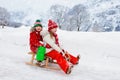 Little girl and boy enjoying sleigh ride. Child sledding. Toddler kid riding a sledge. Children play outdoors in snow. Kids sled Royalty Free Stock Photo