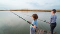 little girl and boy fish on a fishing rod standing on a wooden bridge Royalty Free Stock Photo