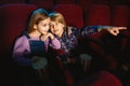 Little girl and boy watching a film at a movie theater