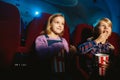 Little girl and boy watching a film at a movie theater