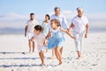 Little girl and boy holding hands while running together on sandy beach while parents and grandparents follow in the Royalty Free Stock Photo