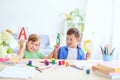 A little girl and a boy learn at home. happy kids at the table with school supplies smiling funny and learning the alphabet in a Royalty Free Stock Photo