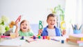A little girl and a boy learn at home. happy kids at the table with school supplies smiling funny and learning the alphabet in a