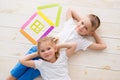 A little girl with a boy lie on the floor next to a house of colored paper. View from above Royalty Free Stock Photo