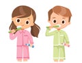 Little girl and boy in pajamas brushing teeth with toothpaste.