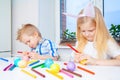 Little girl and boy in rabbit bunny ears on head are preparing for Easter and painting eggs. Colorful markers. Easter, family and Royalty Free Stock Photo