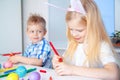 Little girl and boy in rabbit bunny ears on head are preparing for Easter and painting eggs. Colorful markers. Easter, family and Royalty Free Stock Photo