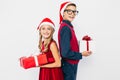 Little girl and boy in Santa hat, stylish brother and sister, happily holding Christmas gifts in their hands, and looking at Royalty Free Stock Photo