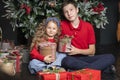 Girl and boy, sister and brother in red clothes with gifts near Christmas tree. Smiling children waiting santa for new year. Happy Royalty Free Stock Photo
