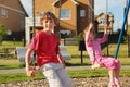 Little girl and boy sit on swing near cottage Royalty Free Stock Photo