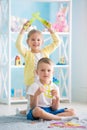 A little girl with a boy is sitting on the floor and holding a house of colored paper. Royalty Free Stock Photo