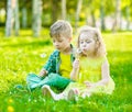 Little girl and boy sitting together on green grass with dandelions Royalty Free Stock Photo