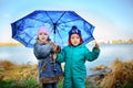 Little girl and boy with umbrella playing in the rain. Kids play outdoor by rainy weather in fall. Autumn fun for children. Toddle Royalty Free Stock Photo