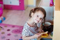 Little girl with braids drawing playing with toy kitchen Royalty Free Stock Photo